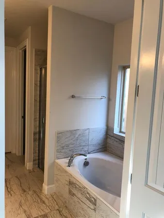 a bathroom with a tub a sink and a large mirror
