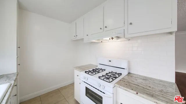 a kitchen with a stove and white cabinets