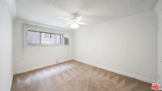 an empty room with a window and a fan