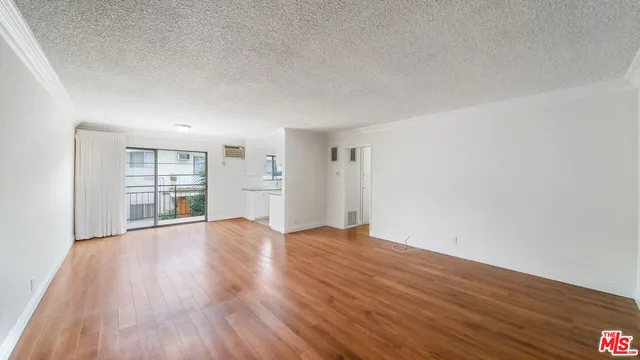 a view of an empty room with wooden floor and windows