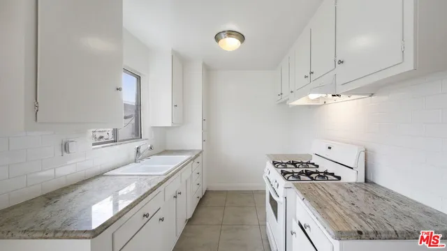 a kitchen with granite countertop a sink stove and cabinets