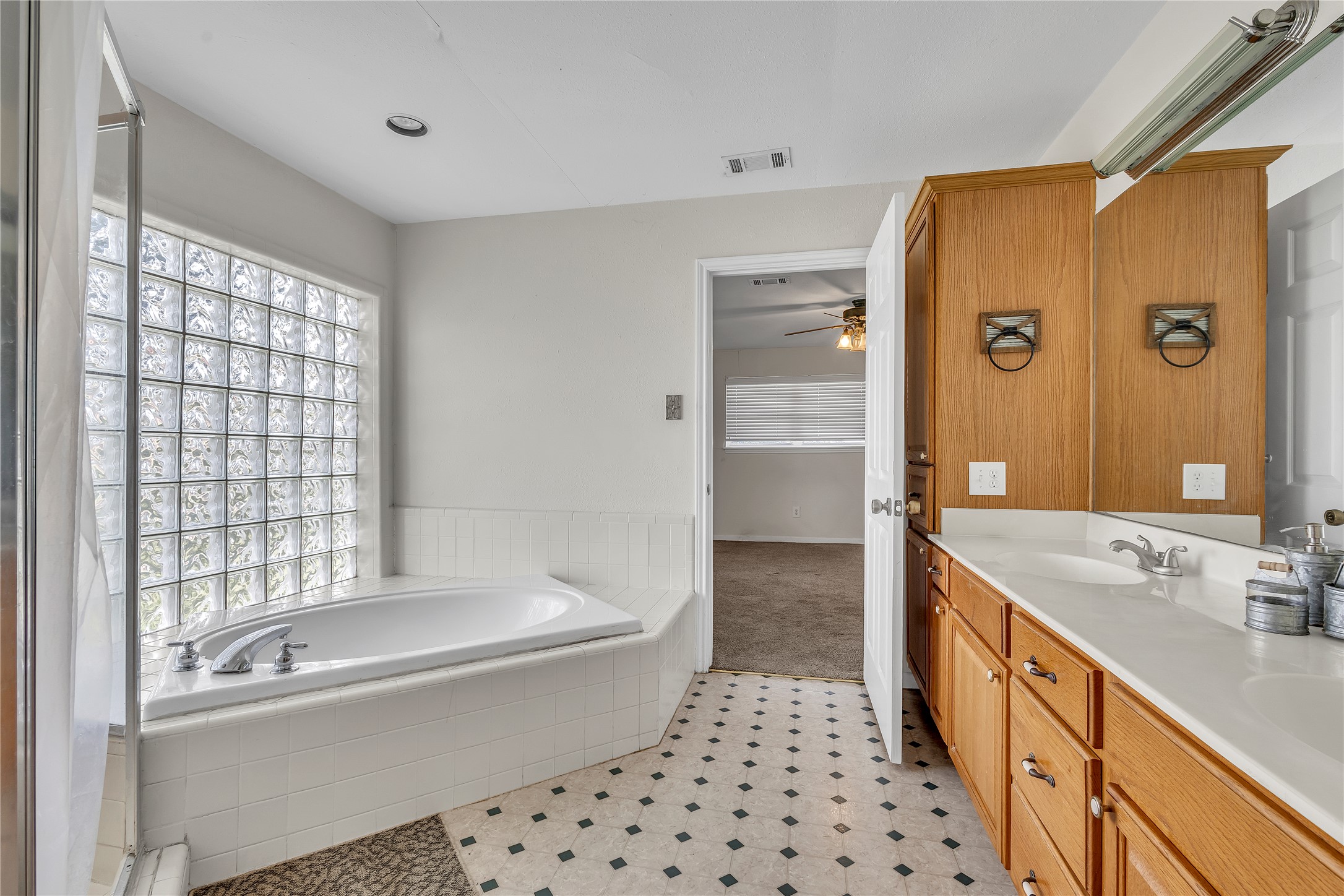 1080 League Line Road Paige, TX 78659 - Photo 17 of 39 An alcove soaking tub sits beneath a privacy glass window beside a long double vanity.