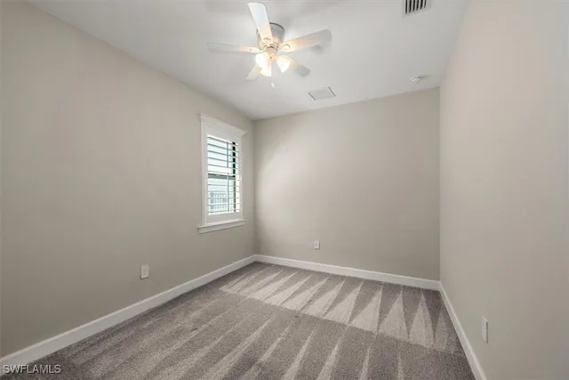 a view of an empty room and chandelier fan