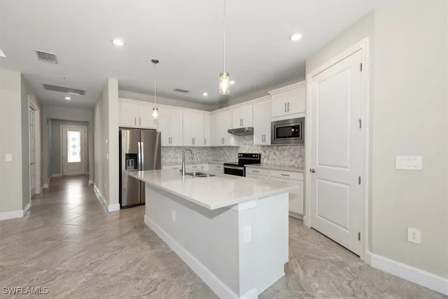 a kitchen with stainless steel appliances kitchen island a refrigerator sink and cabinets