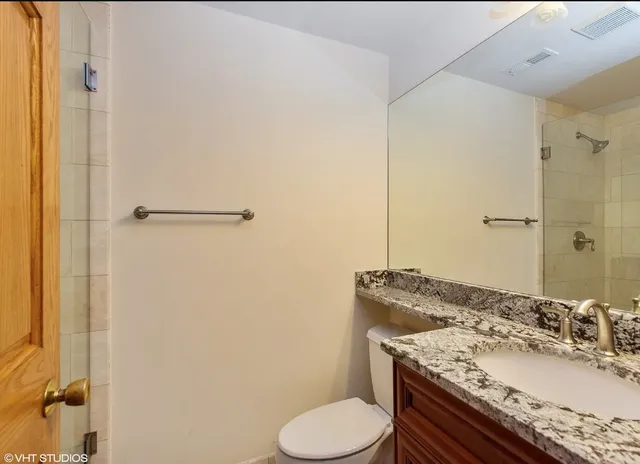a bathroom with a granite countertop sink toilet and shower