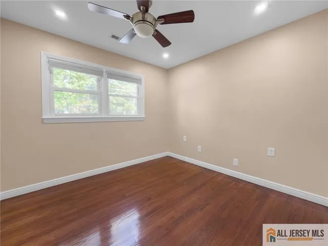 an empty room with wooden floor fan and windows