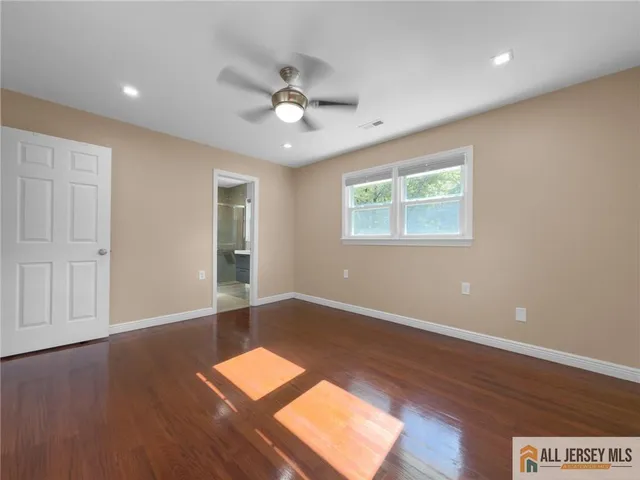an empty room with wooden floor chandelier fan and windows