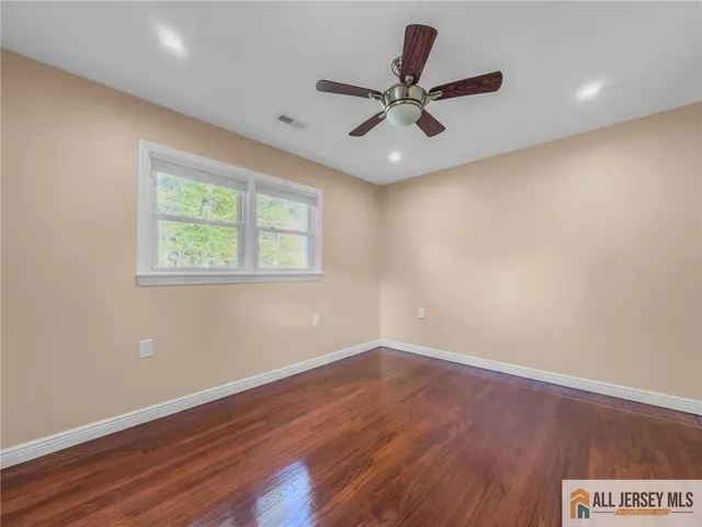 a view of a big room with wooden floor and windows