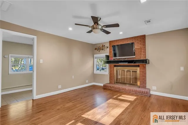 a view of a livingroom with a flat screen tv wooden floor and a ceiling fan