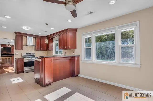 a kitchen with stainless steel appliances granite countertop a refrigerator a sink a stove top oven a large window with a dining table and chairs