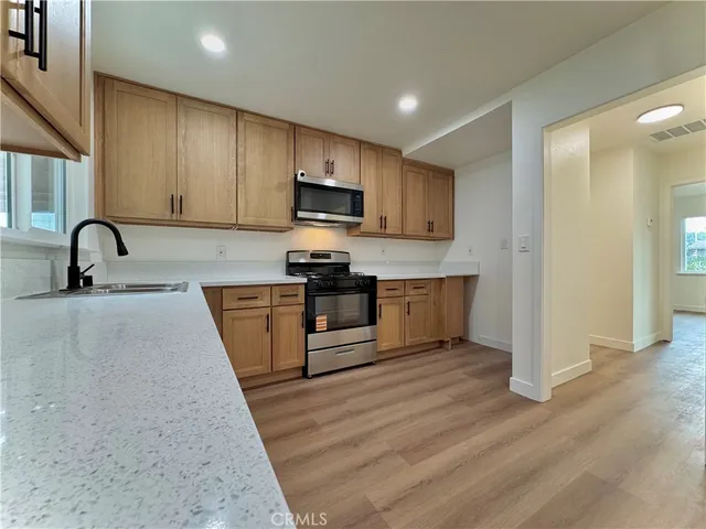 a kitchen with granite countertop a stove a sink and a microwave