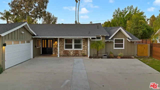a front view of a house with a garden and trees