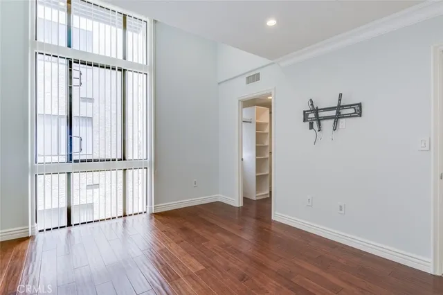 a view of an empty room with wooden floor and closet