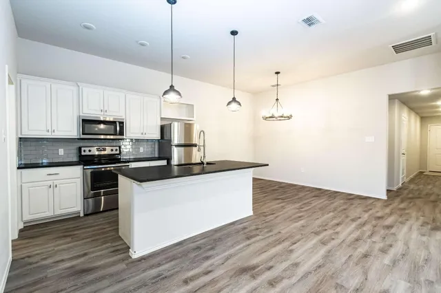 a kitchen with kitchen island white cabinets stainless steel appliances and wooden floor
