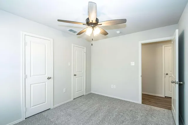 a view of an empty room and chandelier fan