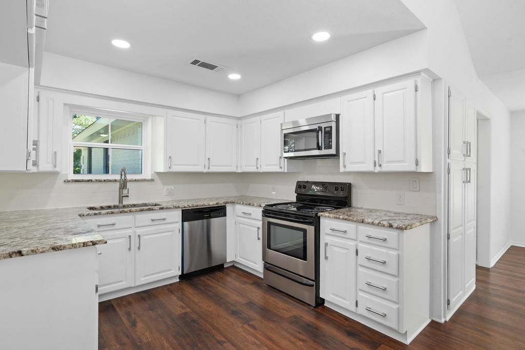 4501 Ridgeway Road Fort Worth, TX 76126 - Photo 16 of 39 a kitchen with stainless steel appliances granite countertop white cabinets a sink a stove a microwave and wooden floors