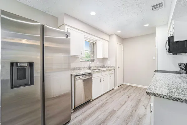 a kitchen with granite countertop a sink stove and refrigerator