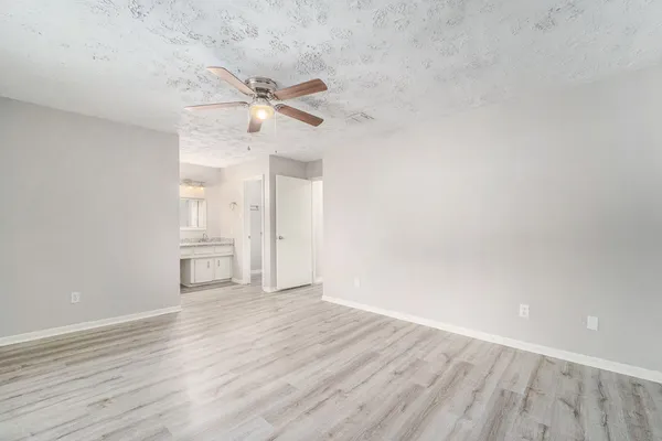 a view of empty room with wooden floor and ceiling fan