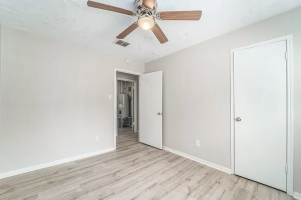 an empty room with wooden floor ceiling fan and windows