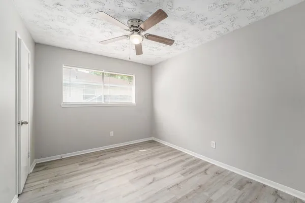 an empty room with wooden floor and windows