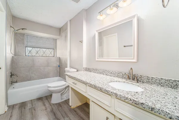 a bathroom with a granite countertop sink toilet a mirror and bathtub