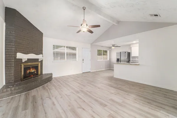 a view of a livingroom with wooden floor a fireplace and windows