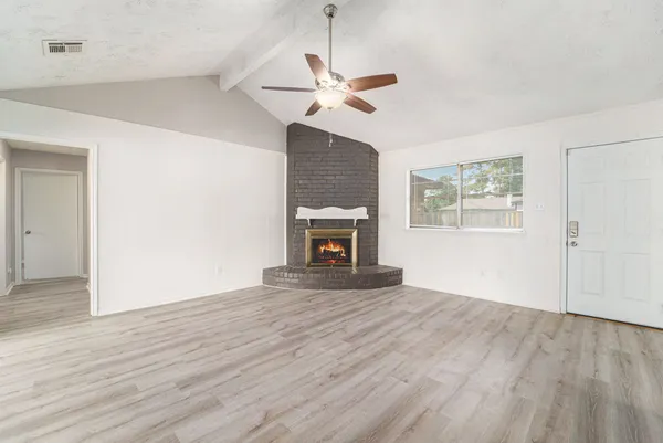 a view of empty room with wooden floor fan and window