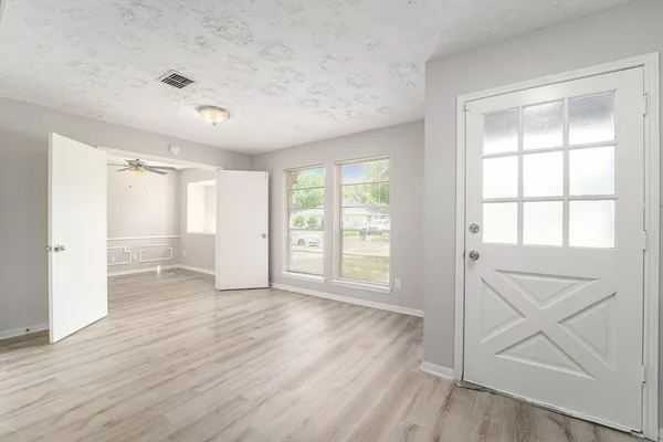 a view of an empty room with wooden floor and a window