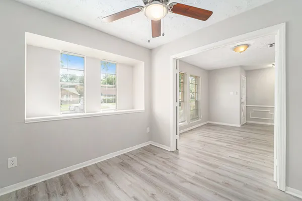 a view of an empty room with wooden floor and a window