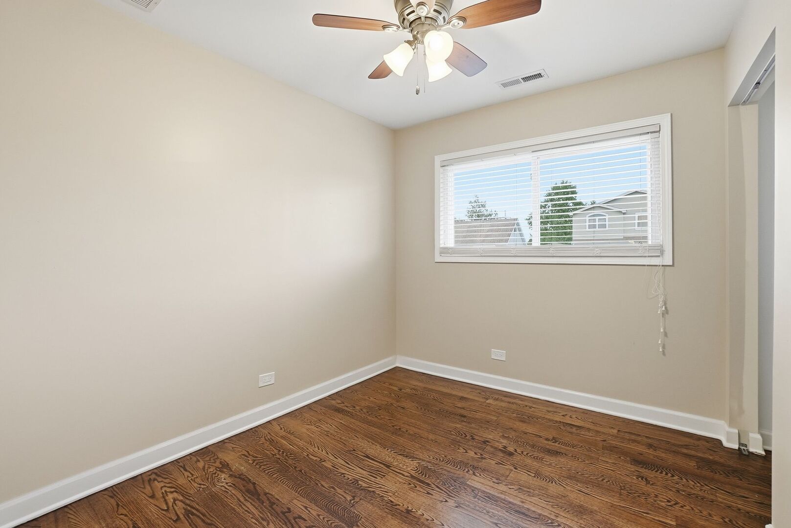 8718 Cranbrook Lane Bridgeview, IL 60455 - Photo 6 of 24 an empty room with wooden floor chandelier fan and windows