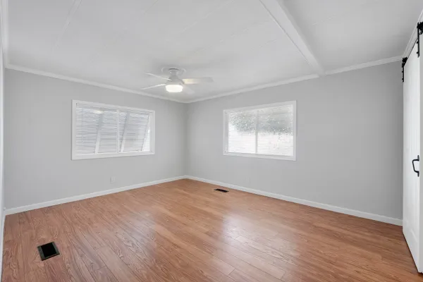 a view of an empty room with wooden floor and a window
