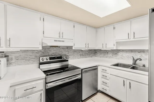 a kitchen with white cabinets stainless steel appliances and sink