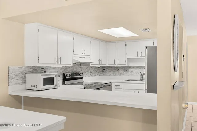 a kitchen with stainless steel appliances white cabinets and a refrigerator