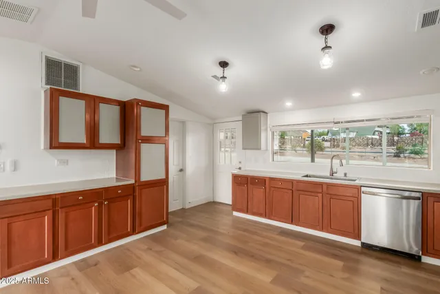 a kitchen with stainless steel appliances granite countertop a refrigerator a sink dishwasher a stove and white countertops with wooden floor