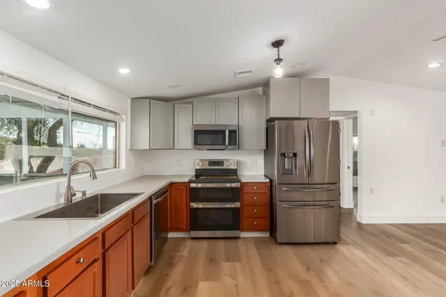 a large kitchen with stainless steel appliances granite countertop a sink and wooden cabinets