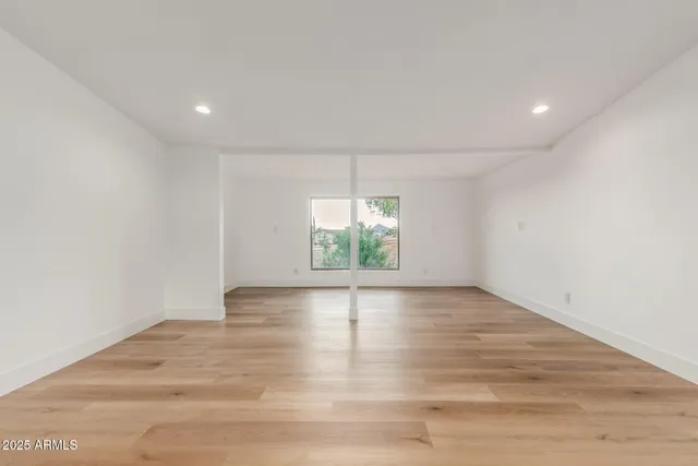 an empty room with wooden floor and a kitchen