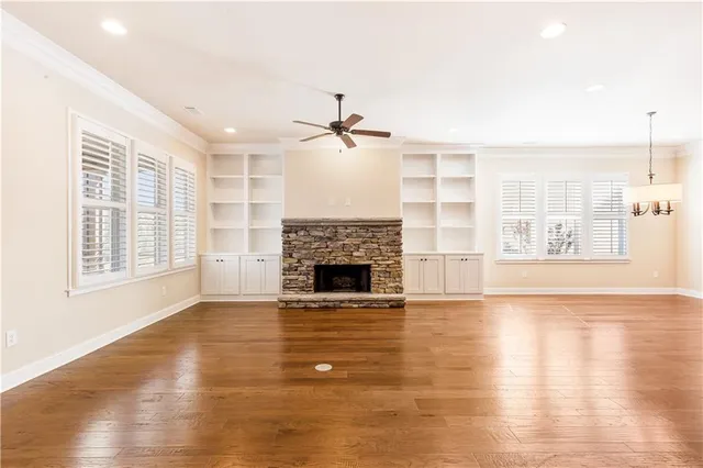 a view of a livingroom with a fireplace a ceiling fan and windows