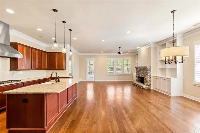a kitchen with stainless steel appliances granite countertop a sink a stove and a wooden floors