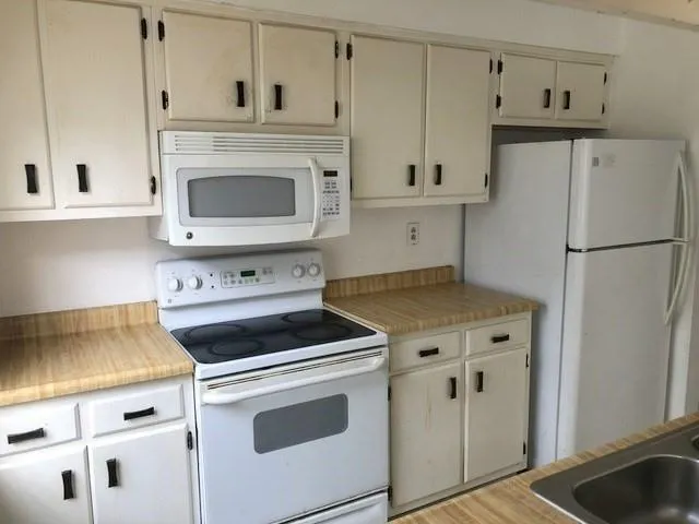 a kitchen with white cabinets and white appliances