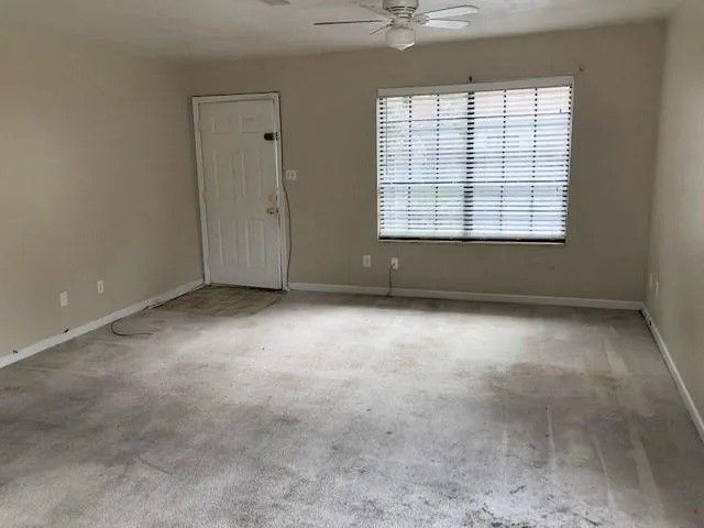 an empty room with windows and chandelier fan