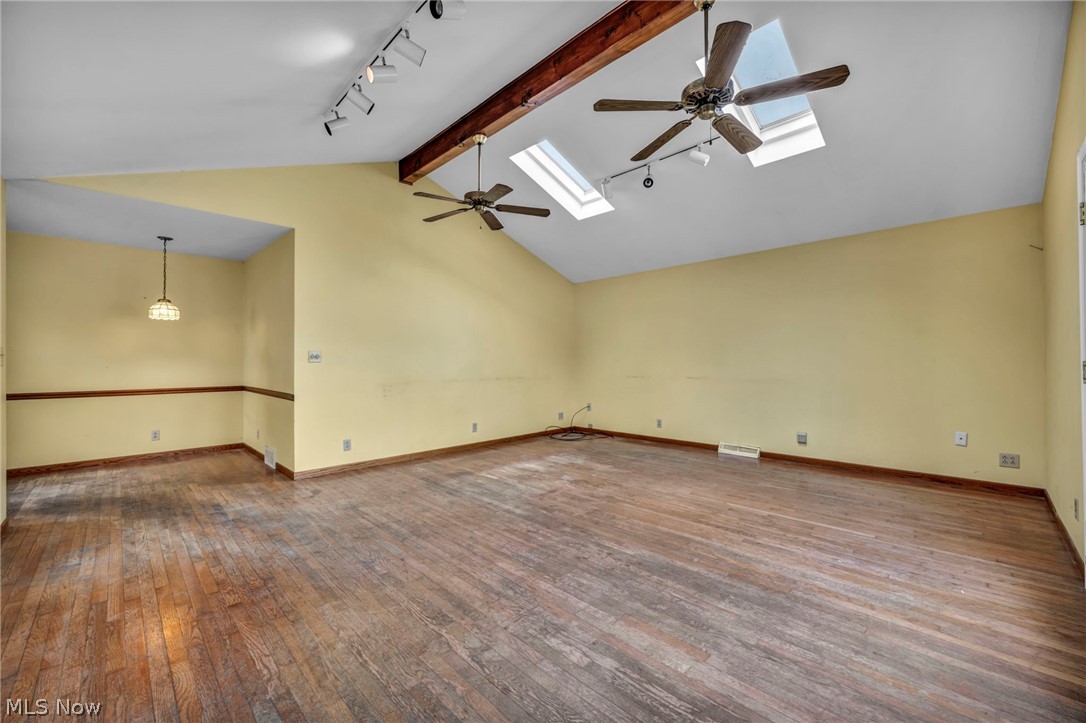 1011 Spring Road Cleveland, OH 44109 - Photo 24 of 47 Unfurnished room featuring rail lighting, ceiling fan, beamed ceiling, dark hardwood / wood-style floors, and a skylight
