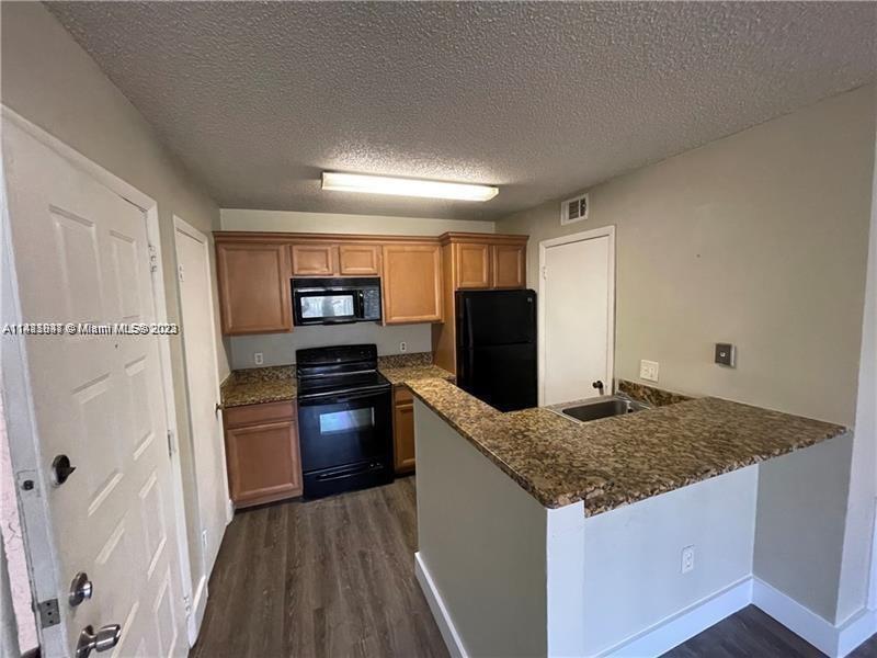 4481 West McNab Road, Unit 25 Pompano Beach, FL 33069 - Photo 3 of 5 a kitchen with granite countertop a refrigerator and a sink