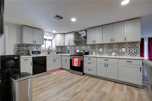 a kitchen with granite countertop a refrigerator sink cabinets and wooden floor