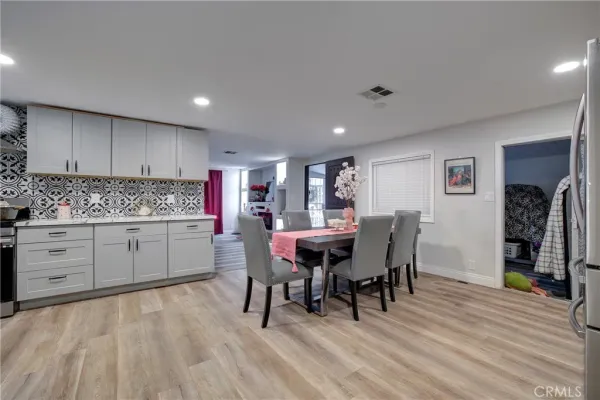 a kitchen with stainless steel appliances kitchen island granite countertop a table chairs a stove a sink and a refrigerator