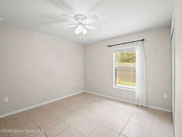 an empty room with chandelier fan and windows