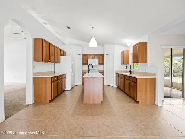 a kitchen with stainless steel appliances granite countertop a stove top oven a sink a refrigerator and white cabinets with wooden floor