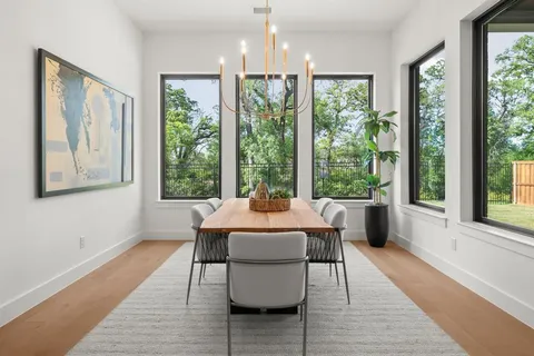 a dining room with wooden floor a chandelier a couch and windows