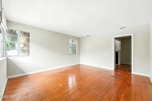 a view of empty room with wooden floor and ceiling fan