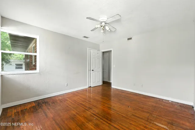 an empty room with wooden floor and a ceiling fan