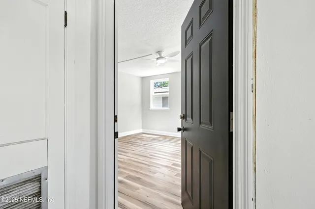 a view of a bedroom with wooden floor and a ceiling fan